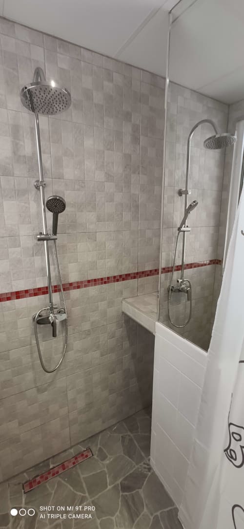 Moderno cuarto de baño con ducha de efecto lluvia doble y alcachofa de mano en Apartamentos Huelintown, Málaga