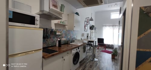 Cocina moderna y sala de estar en Apartamentos Huelintown, Málaga con muebles blancos, azulejos coloridos y diseño abierto