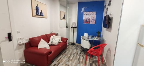 Moderna sala de estar en Apartamentos Huelintown de Málaga con sofá rojo, pared azul y diseño contemporáneo