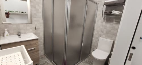 Baño moderno en Apartamentos Huelintown, Málaga con ducha, lavabo, inodoro y paredes alicatadas