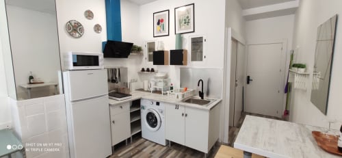 Pequeña cocina moderna en Apartamentos Huelintown en Málaga con electrodomésticos blancos, lavadora y distribución compacta