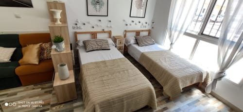 Luminoso dormitorio en Apartamentos Huelintown de Málaga con dos camas individuales de sábanas rayadas, muebles de madera y
