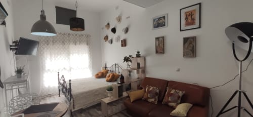 Moderno estudio en Apartamentos Huelintown, Málaga, con cama, sofá, lámparas colgantes y decoración mural