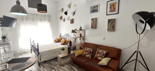 Estudio en Apartamentos Huelintown, Málaga, con sofá marrón, cama, TV y decoración moderna