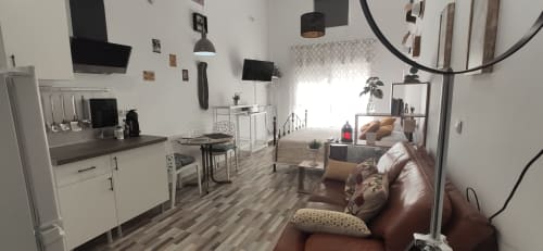 Moderno estudio en Apartamentos Huelintown, Málaga, con sofá de cuero, kitchenette y mobiliario contemporáneo
