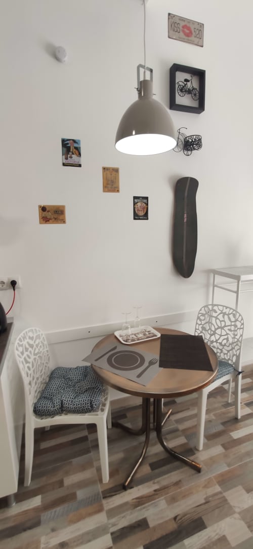 Zona de comedor moderna en Apartamentos Huelintown con mesa redonda, sillas blancas, lámpara colgante y arte mural en Málaga
