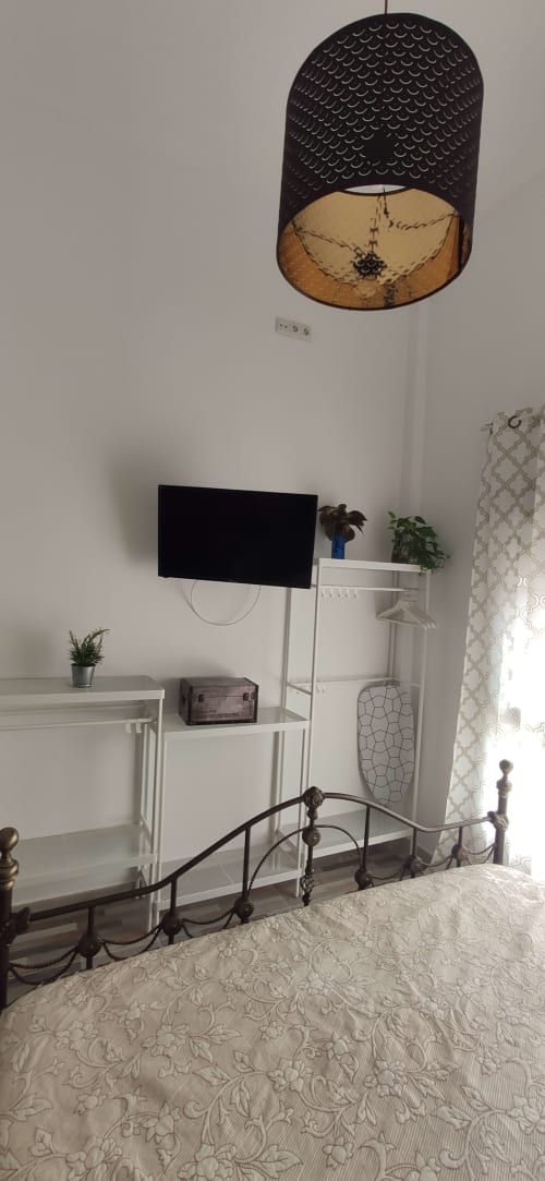 Dormitorio moderno en Apartamentos Huelintown con televisor de pantalla plana, unidad de almacenamiento blanca y lámpara colgante decorativa