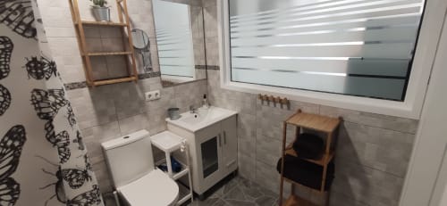 Baño moderno en Apartamentos Huelintown en Málaga con inodoro, lavamanos, ducha y estantería de madera