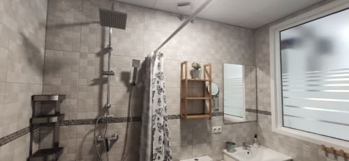 Baño moderno en Apartamentos Huelintown en Málaga con ducha a ras de suelo, estanterías de madera y paredes alicatadas