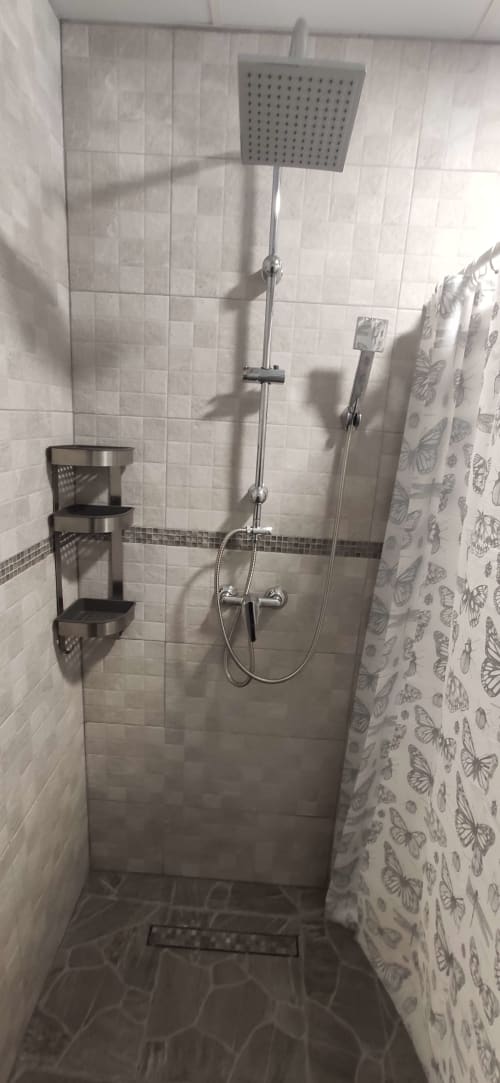 Baño moderno con alcachofa de ducha cuadrada y grifo mural en apartamento de Apartamentos Huelintown Málaga