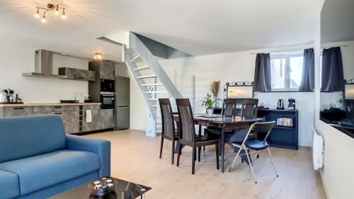 Appartement T3 moderne à la Résidence L'Hermitière : séjour ouvert, cuisine équipée, salle à manger, canapé bleu et escalier