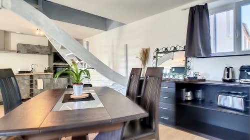 Cuisine ouverte et salle à manger modernes à la Résidence L'Hermitière avec table en bois, électroménagers noirs et escalier