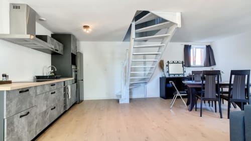 Appartement contemporain ouvert avec cuisine, salle à manger et escalier vers mezzanine à la Résidence L'Hermitière