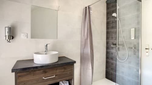 Salle de bain moderne de l'Appartement T3 n°5 à la Résidence L'Hermitière avec vasque, douche à l'italienne et carrelage foncé