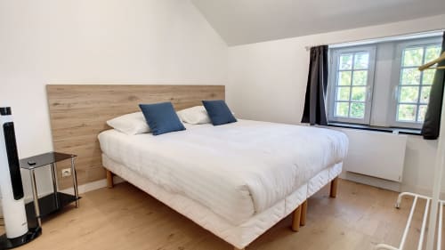 Chambre lumineuse à la Résidence L'Hermitière avec lit en bois, literie blanche, fenêtres sur jardin et parquet