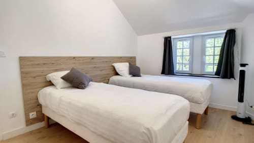 Chambre lumineuse avec deux lits jumeaux, tête de lit en bois et vue sur le jardin à Résidence L'Hermitière