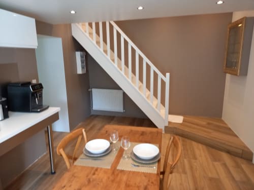 Appartement ouvert au Moulin de la Chevanne avec table à manger, cuisine et escalier, parquet