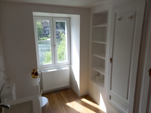 Chambre lumineuse au Moulin de la Chevanne avec parquet, portes blanches, radiateur et portes-fenêtres ouvrant sur