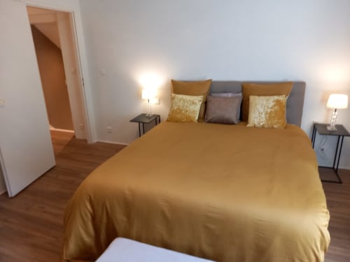 Chambre moderne du Moulin de la Chevanne B&B à Champlive avec literie dorée, tête de lit grise et lampes de chevet