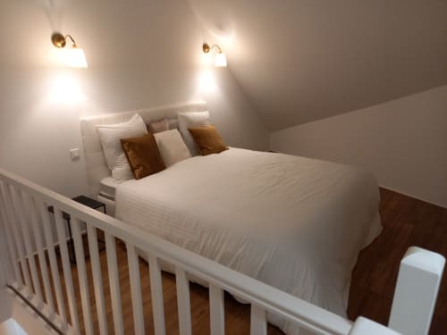 Chambre loft moderne au Moulin de la Chevanne avec lit queen-size, appliques murales en laiton et balustrades blanches à Champlive