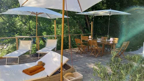 Terrasse avec transats, parasols et coin repas offrant vue sur la verdure au Moulin de la Chevanne, Champlive