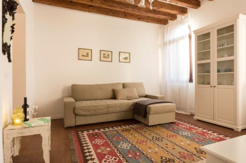 Accogliente appartamento veneziano L'Altalena di Francesca con divano componibile beige, travi in legno a vista, tappeto decorato e porta in vetro