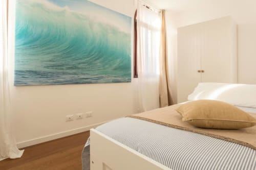 Bright bedroom in Venice apartment with turquoise ocean wave artwork, wooden floor, and coastal-inspired decor