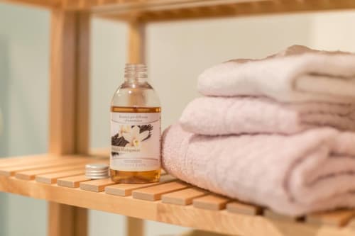 Vanilla diffuser and folded towels on wooden shelf at Ca Cortigiane, Venice apartment