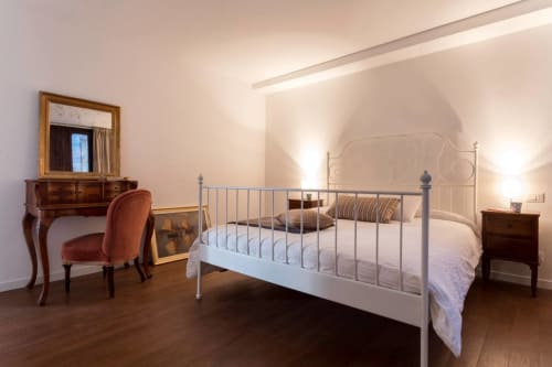 Elegant bedroom at Ca Cortigiane in Venice featuring white metal bed, wooden furniture, and ambient lighting
