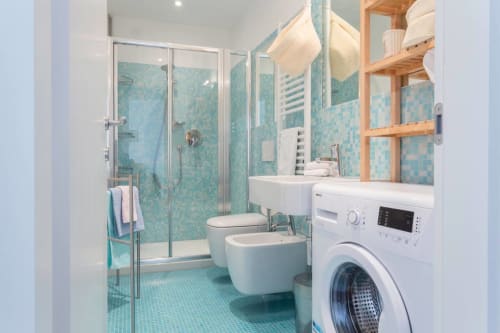 Modern bathroom at Ca Cortigiane Venice apartment with turquoise tile, shower, bidet, toilet, and washing machine