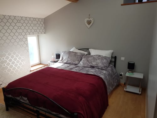 Cozy bedroom at Le Pommier B&B in Clussais-la-Pommeraie with burgundy bedding, gray accents, and window light
