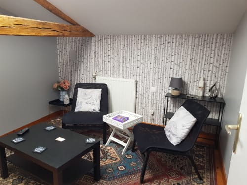 Salon cosy au Pommier avec papier peint bouleau, mobilier noir, poutre apparente et touches décoratives