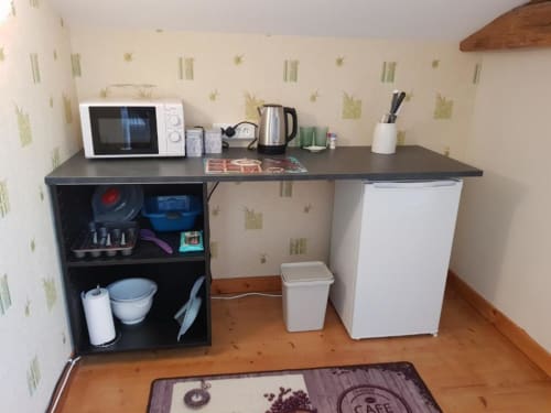 Kitchenette de l'appartement Le Pommier avec micro-ondes, bouilloire, mini-réfrigérateur et étagères de rangement à Clussais-la-Pommeraie.