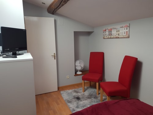 Chaises rouges dans la chambre de l'appartement Le Pommier avec bureau, porte et poutres en bois à Clussais-la-Pommeraie