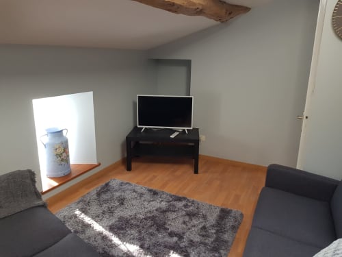 Séjour dans l'appartement deux chambres du Pommier Chambre d'Hôte, avec télévision, tapis gris, parquets et poutres rustiques