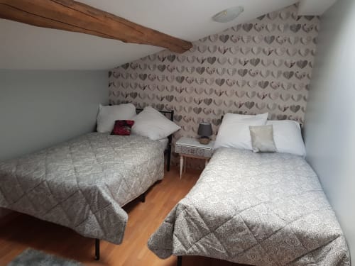 Chambre accueillante aux lits jumeaux au Pommier avec papier peint à motifs de cœurs et poutres apparentes