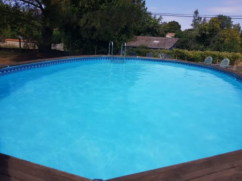 Piscine cristalline de la Chambre d'hôte Le Pommier à Clussais-la-Pommeraie, entourée d'arbres et de chaises longues