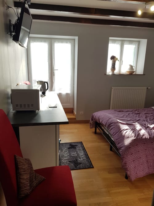 Chambre lumineuse au Pommier Chambre D'hôte à Clussais-la-Pommeraie avec literie violette, bureau, portes-fenêtres et