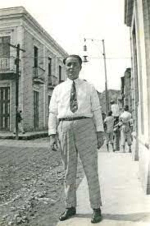 Hombre con camisa blanca y corbata de pie en una calle de Miyares, Piloña, España, cerca del hotel La Venta de Miyares
