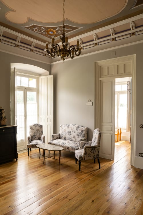 Elegante salón con techo ornamentado, araña de bronce, muebles florales y pisos de madera en el hotel La Venta de Miyares