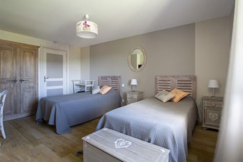 Chambre spacieuse à La Maison De Siloe B&B à Villefranche de Rouergue avec deux lits, mobilier en bois et décoration élégante