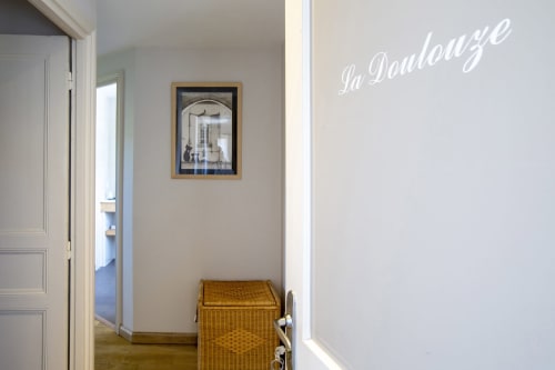 Couloir de La Maison De Siloe avec panier en osier, art mural encadré et inscription 'La Douloyze' à Villefranche-de-Rouergue