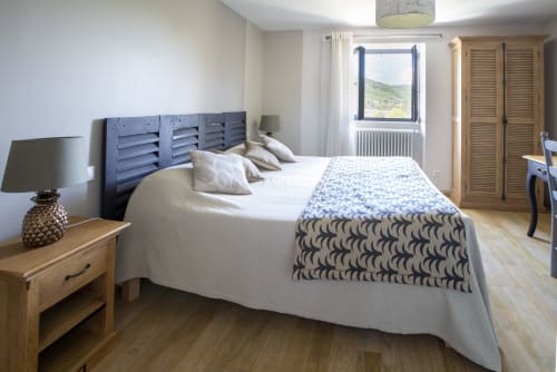 Chambre lumineuse à La Maison De Siloe B&B à Villefranche de Rouergue avec tête de lit bleue, literie blanche et vue sur les montagnes