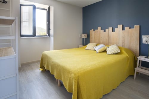 Chambre lumineuse avec lit jaune et tête de lit en bois à La Maison De Siloe, Villefranche de Rouergue