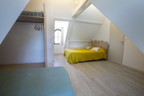 Chambre lumineuse sous les toits à La Maison De Siloe à Villefranche de Rouergue avec lit jaune, puits de lumière et parquet