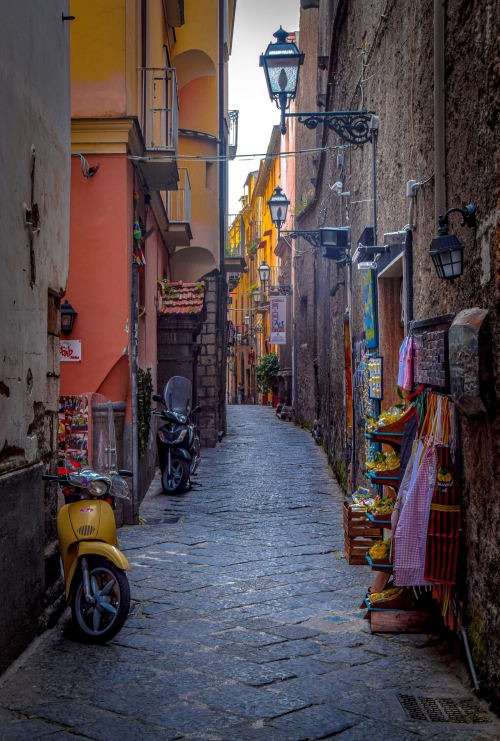 Colorful narrow cobblestone alley in Naples with yellow scooters, traditional buildings, and street lanterns near B&B Il