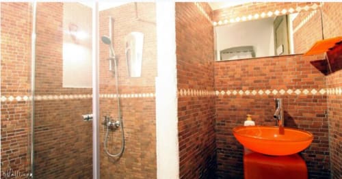 Salle de bain moderne de l'Appartement Casté à l'Agritourisme Stecadò, Dolceacqua, avec lavabo rouge, murs en brique, douche et miroir