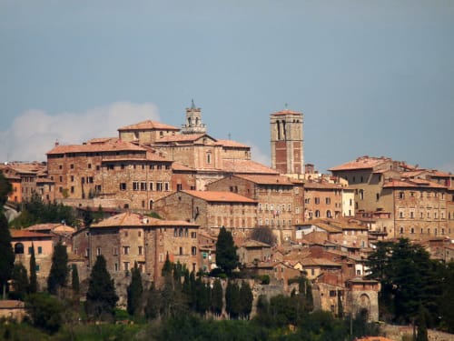 Suggestivo borgo storico di Montepulciano con edifici in terracotta e cipressi, sede della Locanda del Vino Nobile