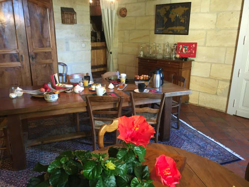 Salle à manger du Sous Les Marronniers B&B avec table en bois, hibiscus rouges et petit-déjeuner