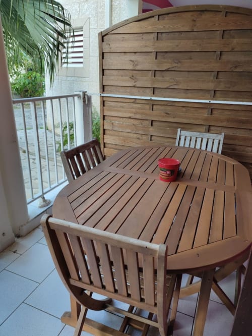 Espace repas extérieur à la Résidence Les 2 Moulins avec table en bois, chaises et jardinières sur balcon à Le Moule, Guadeloupe